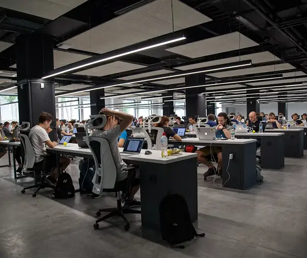 People working at desks in a modern office, with some wearing VR headsets.