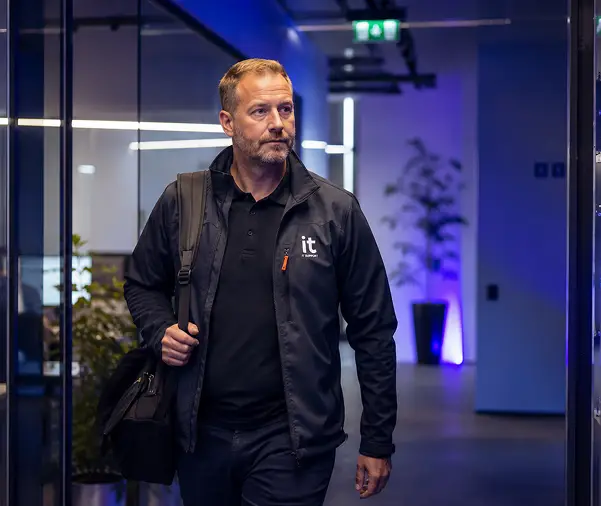 IT support professional walking in office hallway with IT Support jacket